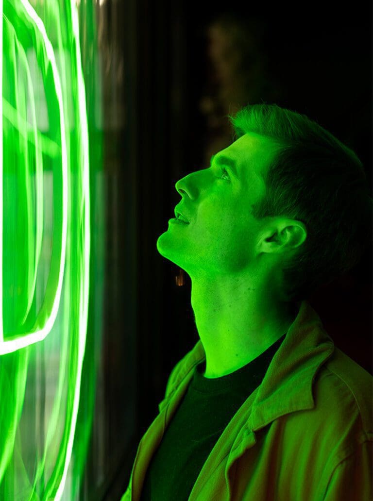 Un hombre mirando un letrero de neón personalizado verde.