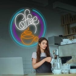 Una mujer está parada frente a un letrero circular de café de neón.