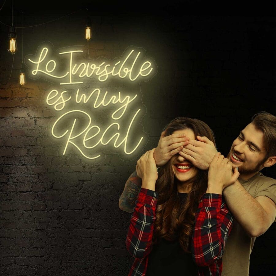 Una pareja cogida de la mano bajo luces Neón Lo invisible es muy Real los ilumina.