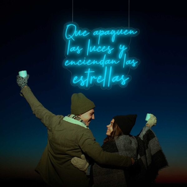 Una pareja sosteniendo un letrero de neón que dice "Neón Que apaguen las luces y enciendan las estrellas".