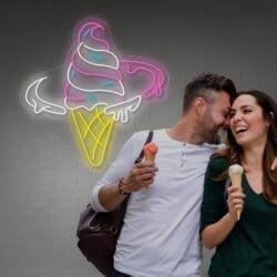 Una pareja riendo y compartiendo Neón Cucurucho Helado junto a una pared con un letrero de neón "Helado Refrescante".